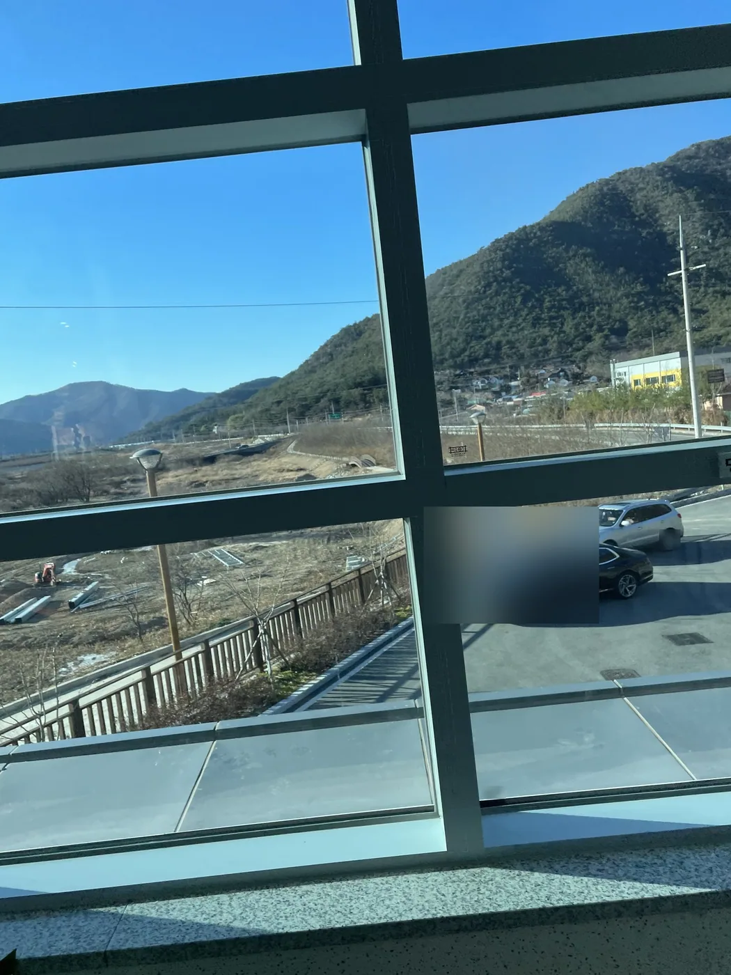 청소를 마친 계단실 격자 유리창 너머로 산자락이 보이는 모습