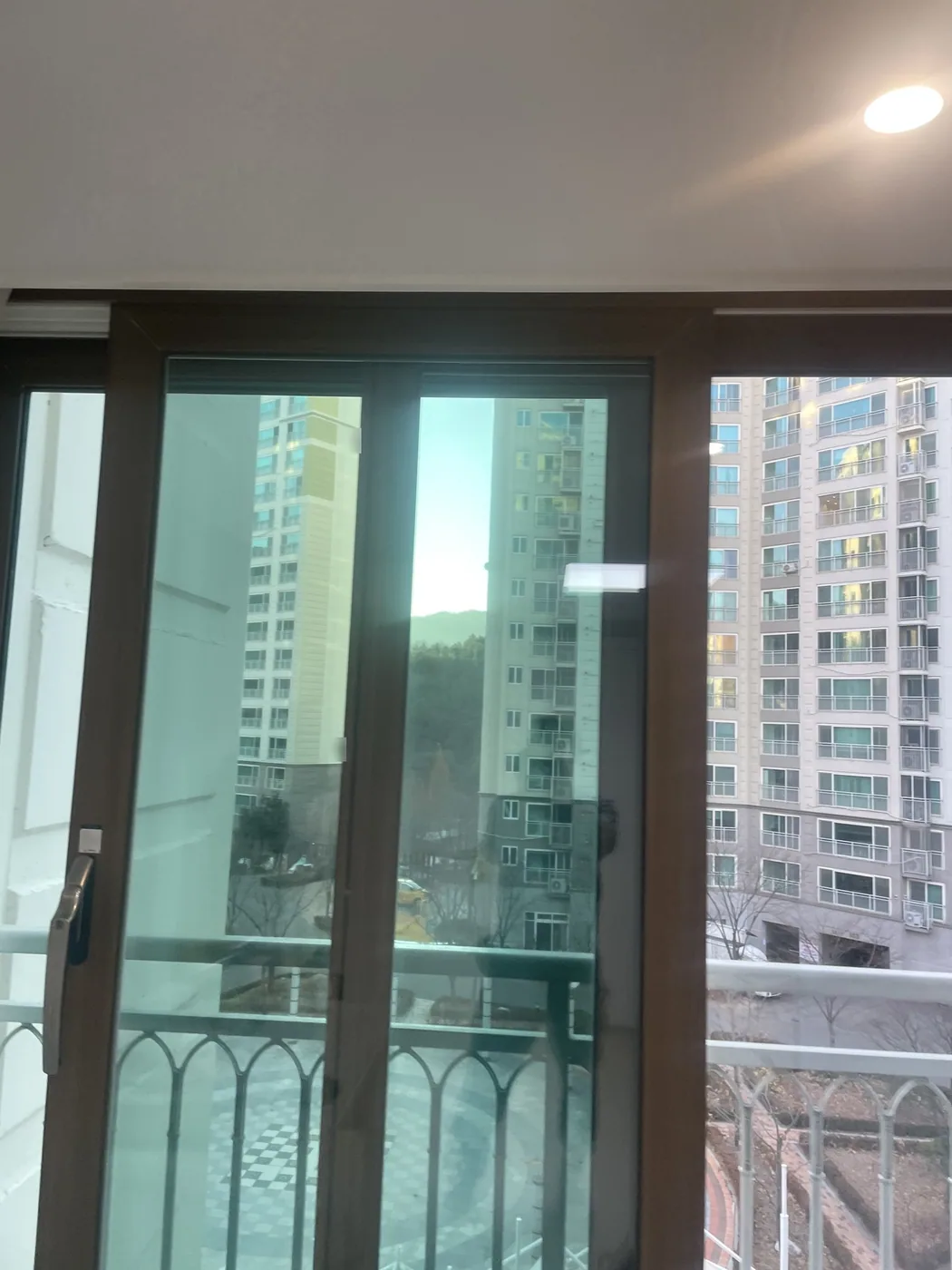 유리와 레일 정리를 마친 방 창과 바깥 난간, 맞은편 아파트 동