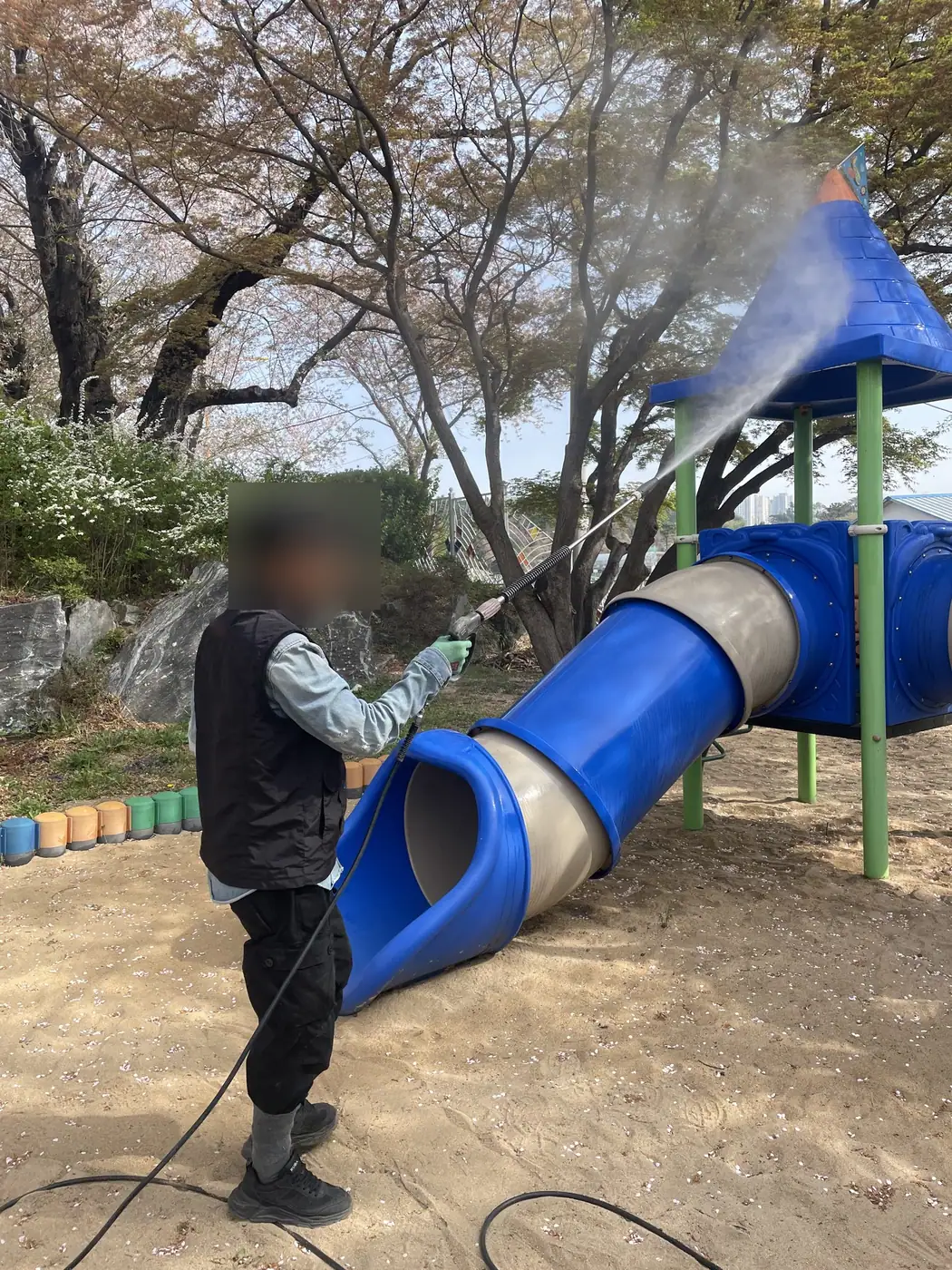 작업자가 고압 세척건으로 튜브 미끄럼틀 겉면에 물을 뿌리는 모습