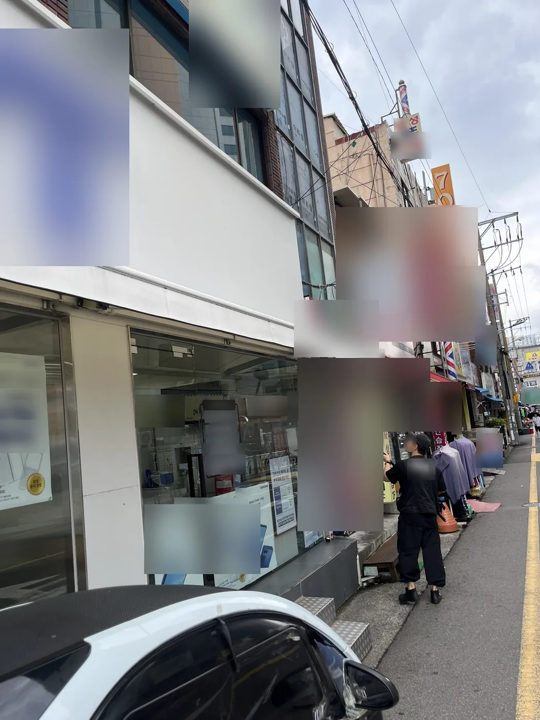 매장 옆면 끝에서 작업자가 긴 막대를 어닝 개폐 고리에 걸어 조작하는 모습