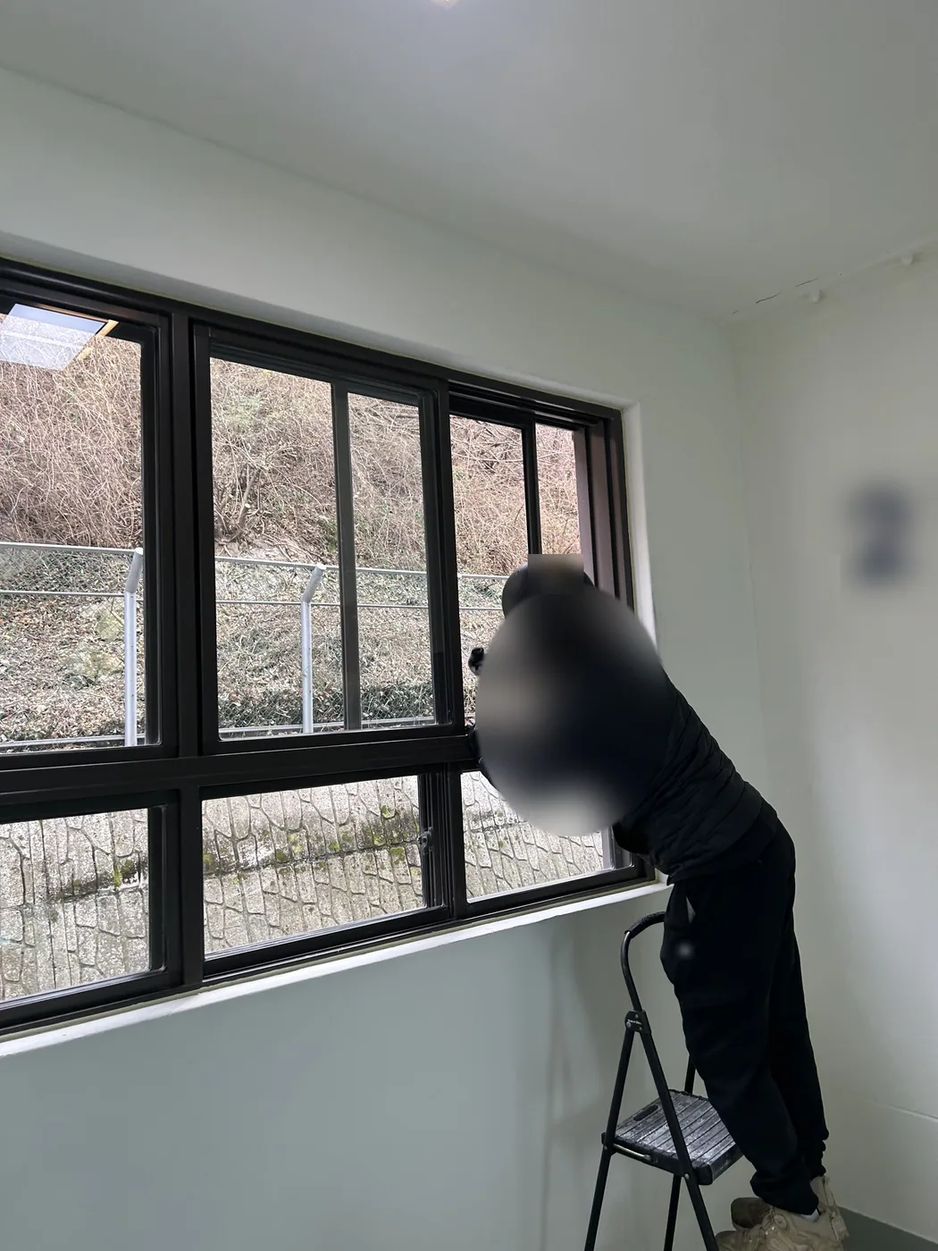 2층 홀 창 앞 발판 사다리에 올라선 작업자가 창 윗부분을 닦는 모습