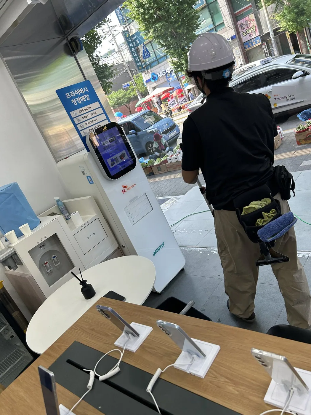 헬멧을 쓴 작업자가 매장 안 진열대 옆에서 통유리를 닦는 뒷모습