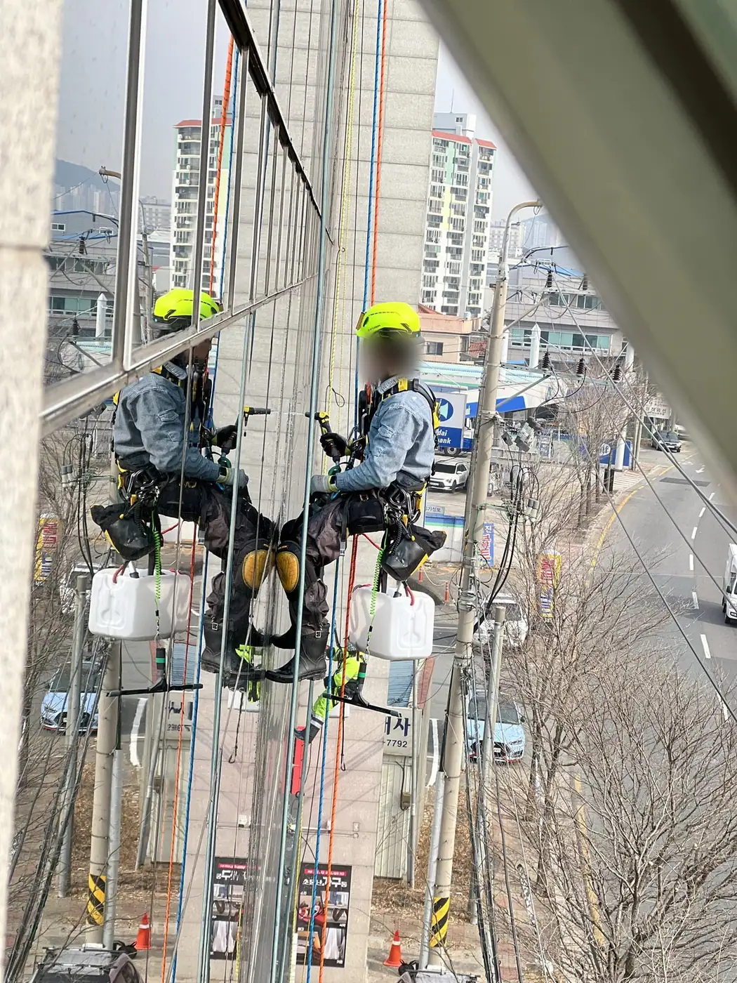 두 작업자가 서로 가까운 거리에서 로프에 매달려 작업하는 근접 장면