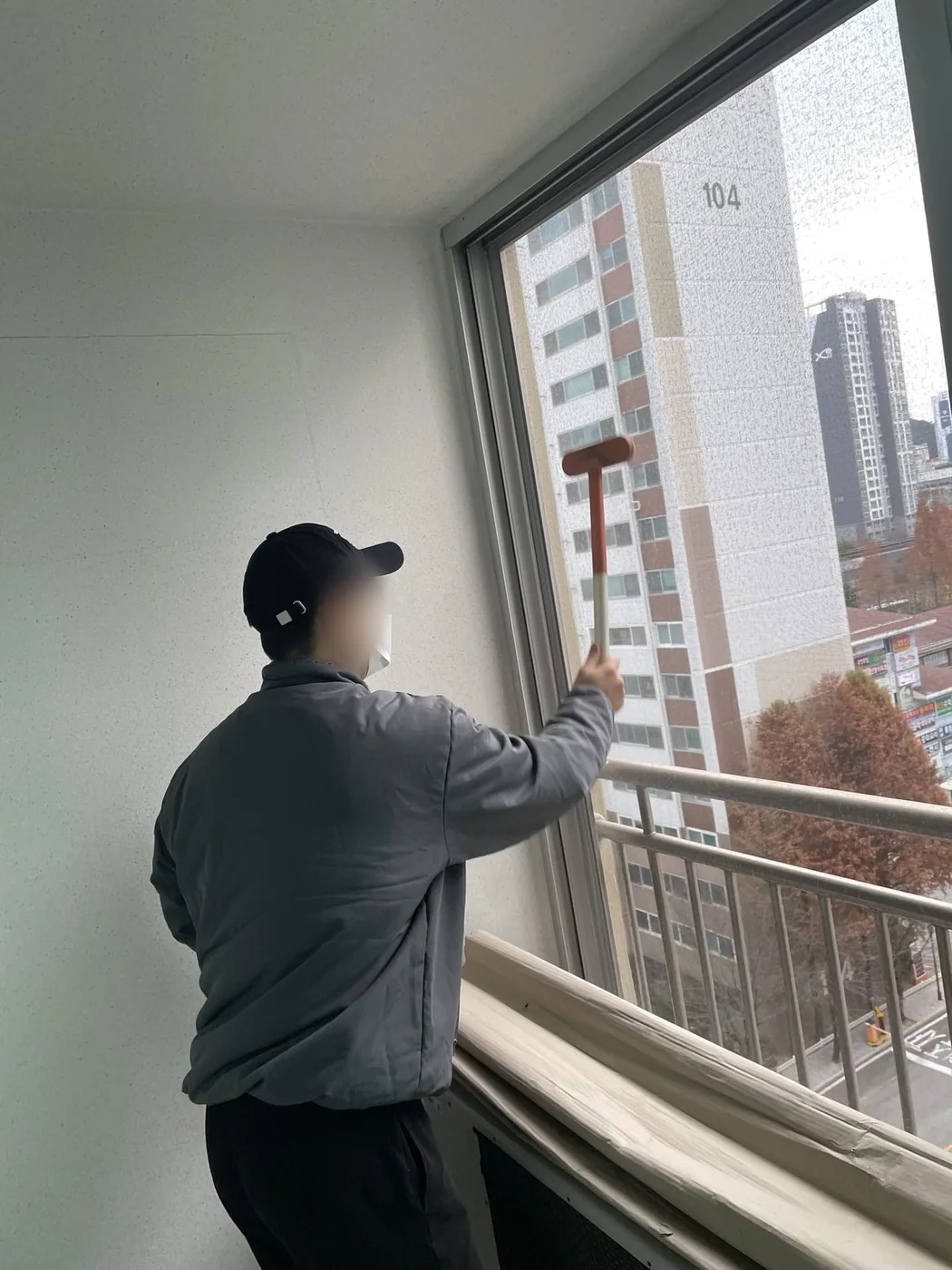 작업자가 베란다 창틀 상부를 손으로 문질러 닦는 장면