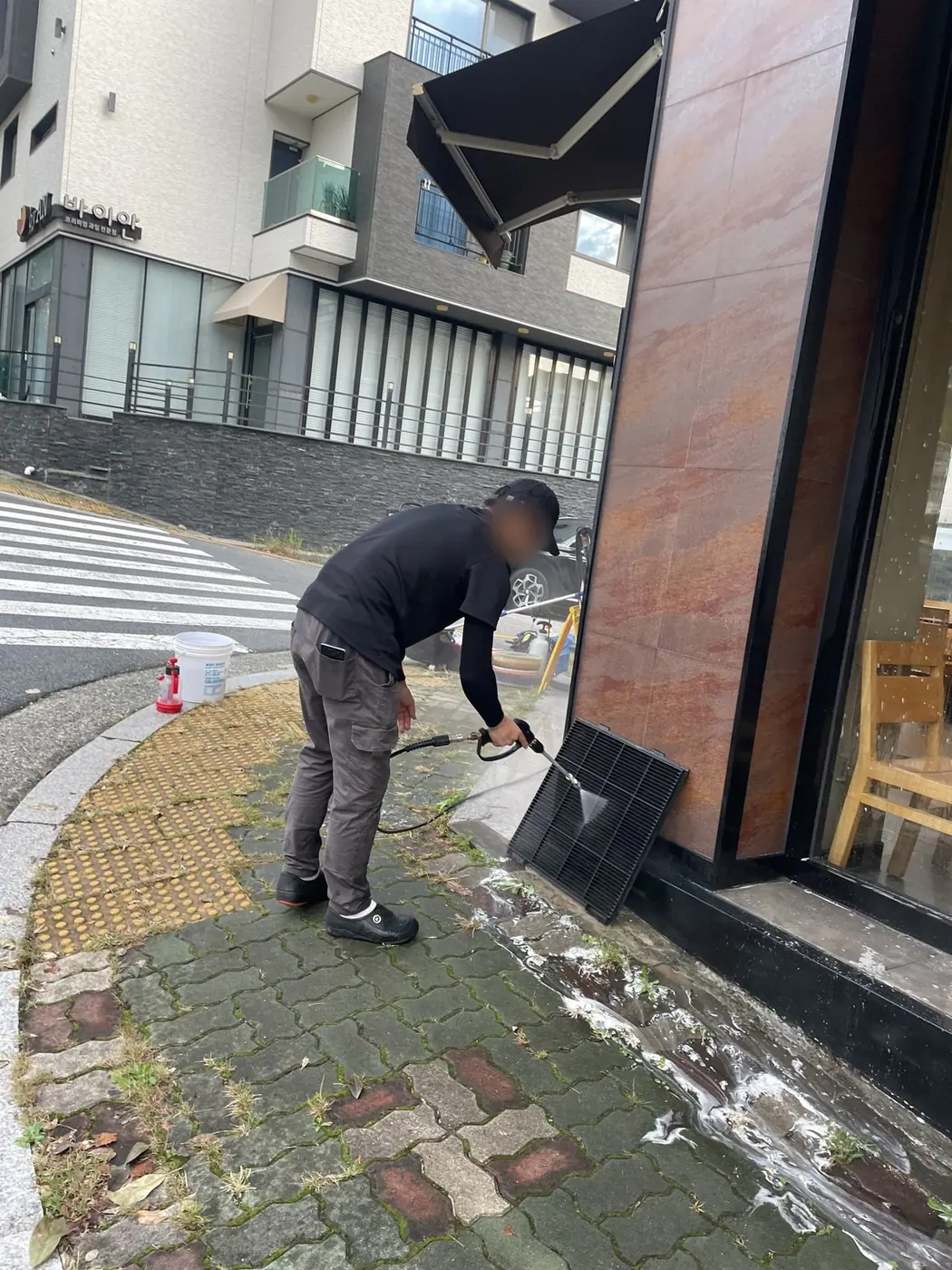 건물 출입구 앞 바닥을 조심스럽게 세척하는 장면