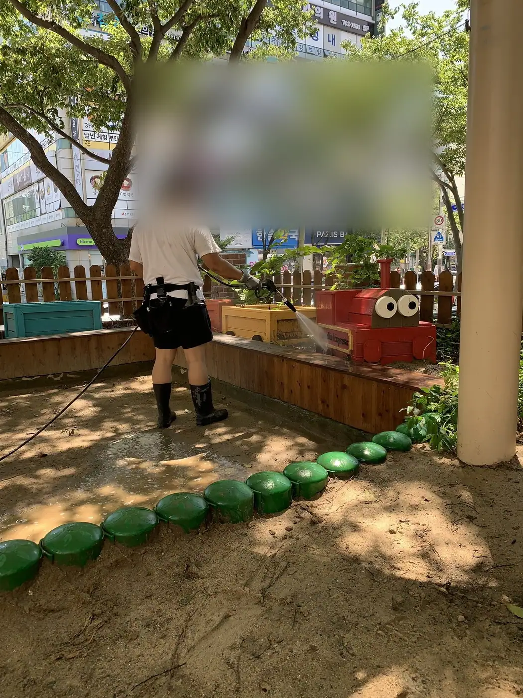 이용이 적은 시간에 놀이터 가장자리를 정리하며 세척하는 장면