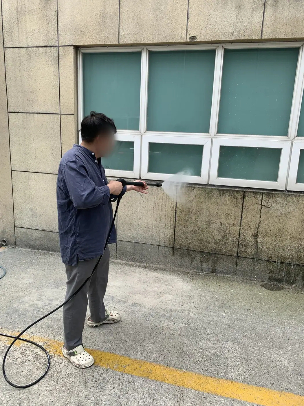 석재 마감 벽면 하부를 세척하며 벽의 상태를 보는 장면