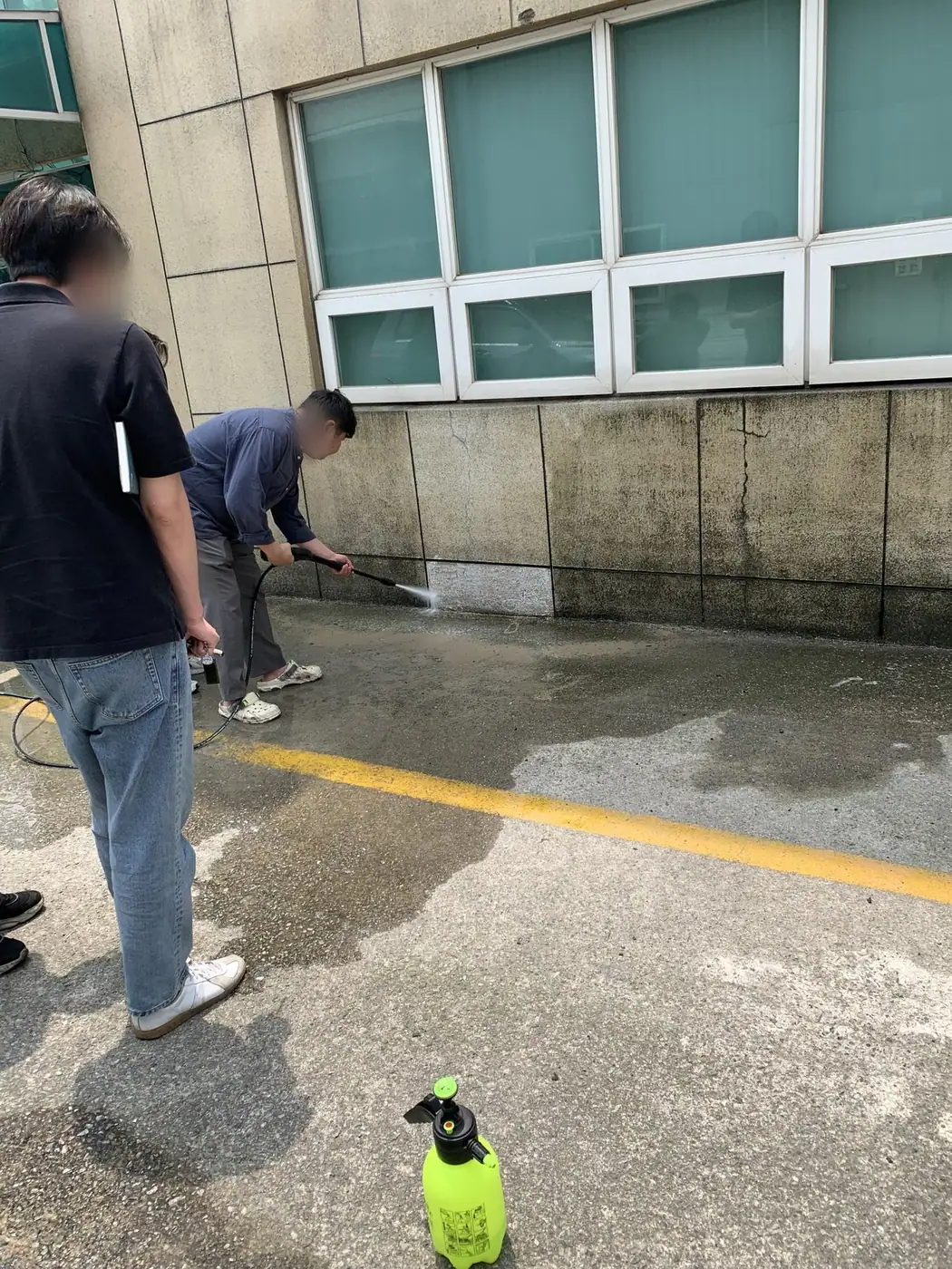 주차 구획 하부의 벽면과 바닥 경계를 세척하는 장면