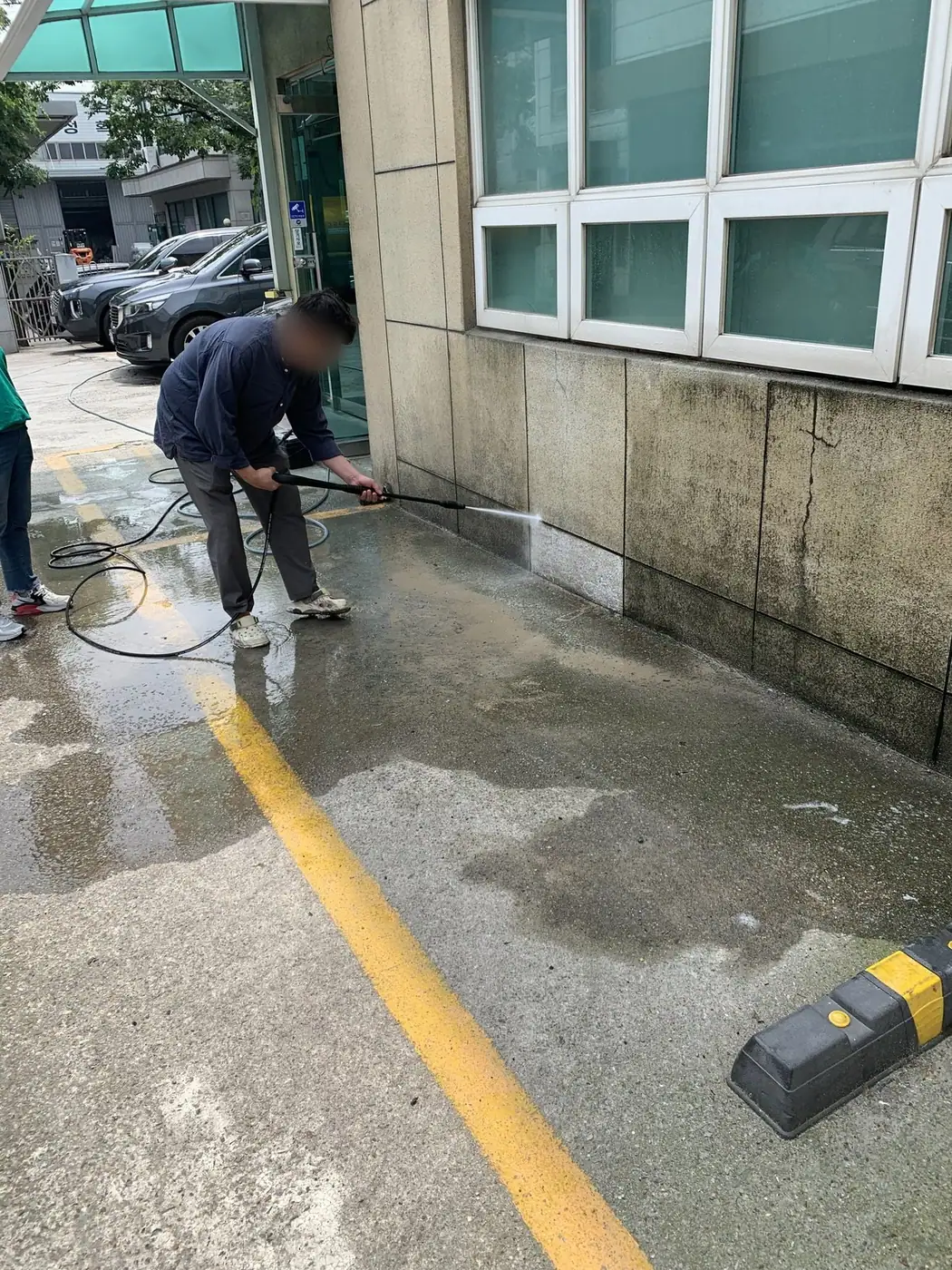 주차 구획에 접한 벽면 하부를 세척하는 장면