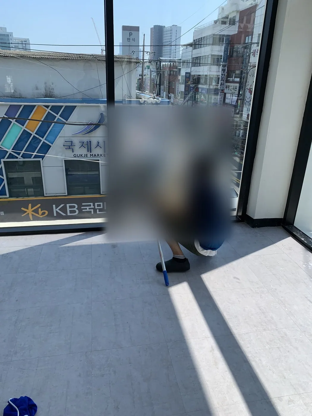 작업자가 무릎을 굽히고 대형 유리면의 하단을 세척하는 장면