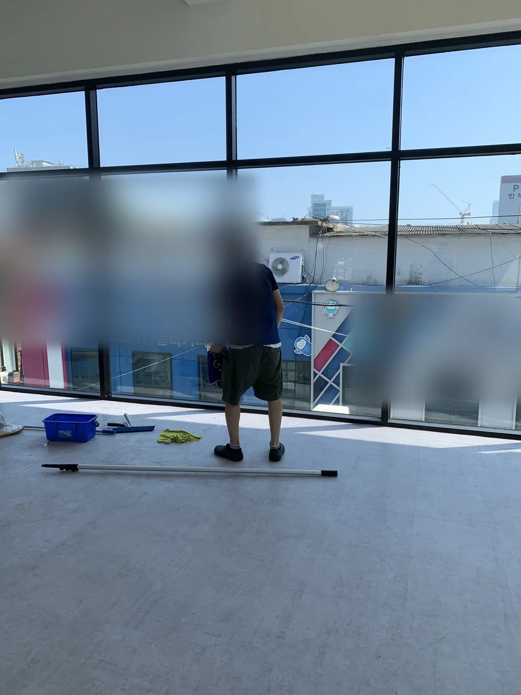대형 유리면 앞에서 작업자가 도구를 정리하며 다음 구간을 살피는 장면