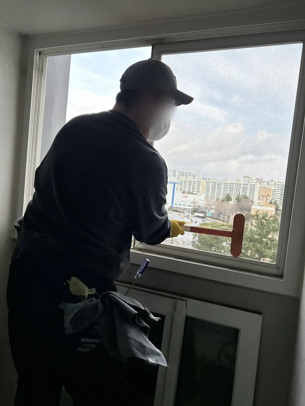 실내에서 작업자가 창유리를 스퀴지로 밀어 물기를 걷어내는 장면