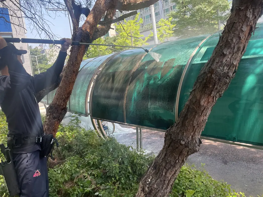 녹색 렉산 캐노피 터널을 고압수로 씻어 내리는 작업자