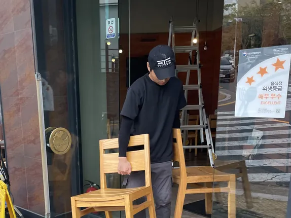 매장 입구 앞에서 의자를 옮기며 작업을 준비하는 작업자